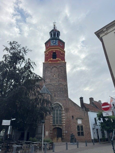 De toren van de kerk in Buren, met de rood met gele klokkenverdieping en de achtkantige lantaarn met spits